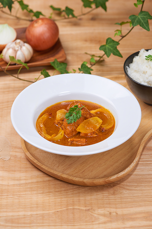 Tasty dinner with chicken curry in bowl on wooden background