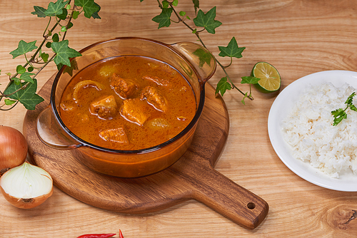 Chicken curry with spice in pot on wooden background