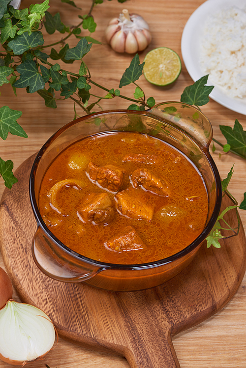 Tasty dinner with chicken curry in bowl on wooden background