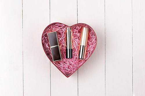 Makeup cosmetics in heart shape box on wooden table. Fflat lay. Top view