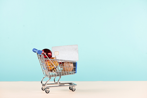 Christmas shopping concept. Shopping cart full with christmas gift boxes and credit card.