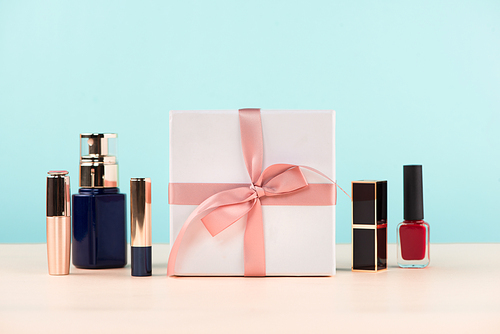 Cosmetics with a present box over blue background.