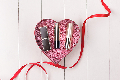 Makeup cosmetics in heart shape box on wooden table. Fflat lay. Top view