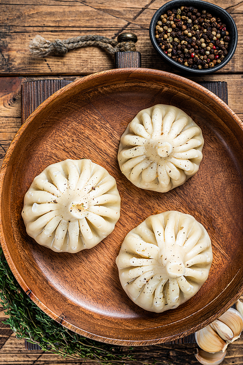 Boiled Khinkali Dumplings with mutton lamb meat in wooden plate. wooden background. Top view.