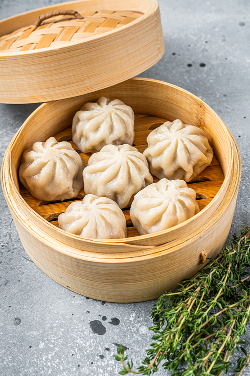 Steamed baozi dumplings stuffed with meat in a bamboo steamer. Gray background. Top view.