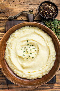 Mashed potatoes, boiled puree in a wooden plate. Wooden background. Top view.