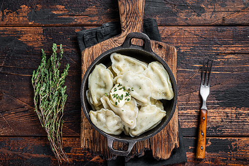 Homemade dumplings, vareniki, pierogi stuffed with potato in a pan. Dark wooden background. Top View.