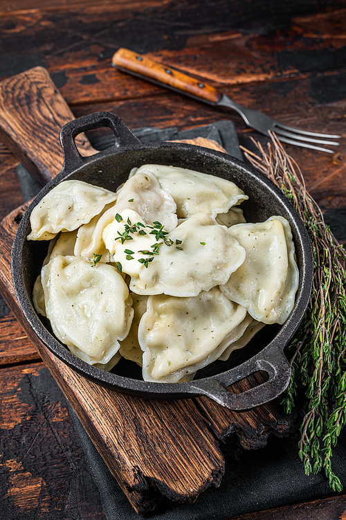 Homemade dumplings, vareniki, pierogi stuffed with potato in a pan. Dark wooden background. Top View.