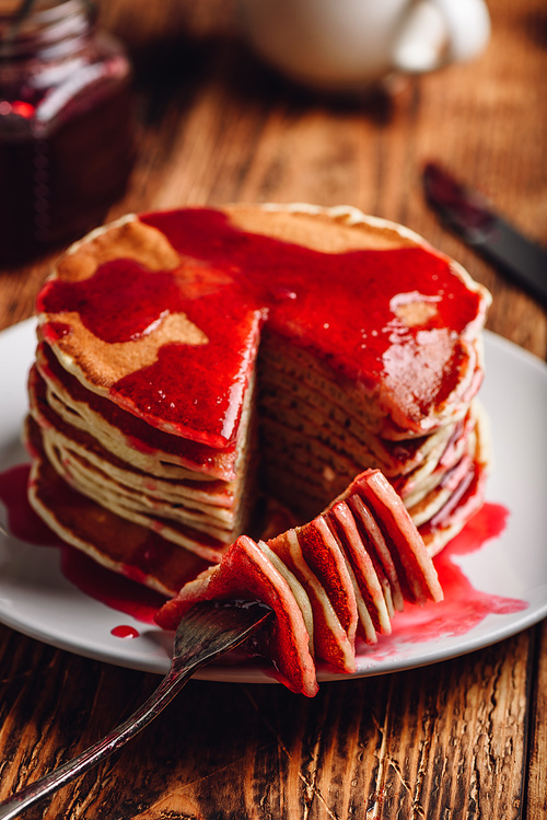 Stack of pancakes with berry fruit marmalade on plate over wooden surface