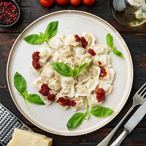Ravioli pasta with mushroom cream sauce and cheese - Italian food style set with basil parmesan and tomatoe  on white plate  on old dark  wooden table background, top view flat lay