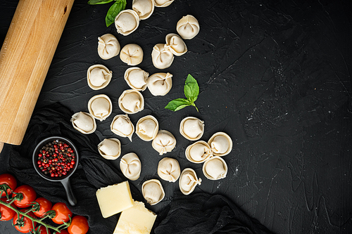 Tasty raw tortellini with flour and basil set, on black background, top view flat lay , with copyspace  and space for text