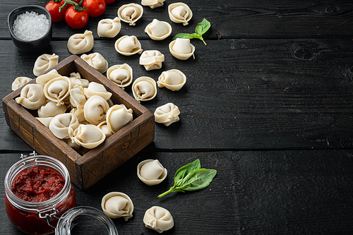 Tasty raw tortellini with flour and basil set, on black wooden table background , with copyspace  and space for text