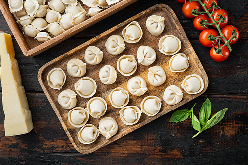 Raw Italian ravioli  tortellini with fresh parmesan and basil , tomatoes set on old dark  wooden table background, top view flat lay