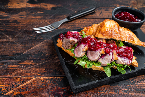 Sandwich with Duck breast fillet steak slices, arugula and sauce. Dark wooden background. Top View. Copy space.
