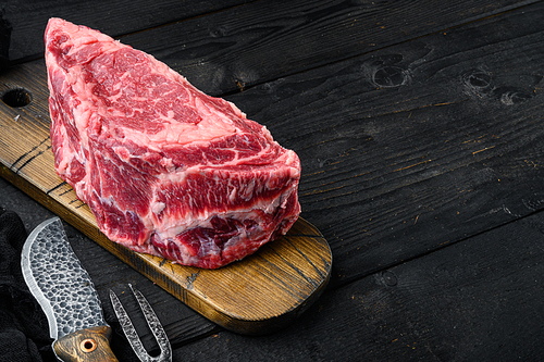 Raw Marble beef black Angus, ribeye or scotch fillet set, on black wooden table background, with copy space for text