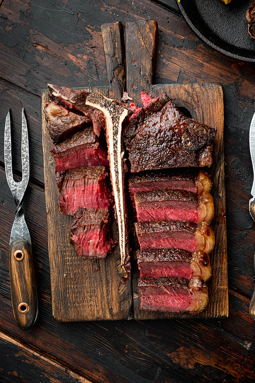 Grilled sliced t bone steak set, on wooden serving board, on old dark  wooden table background, top view flat lay