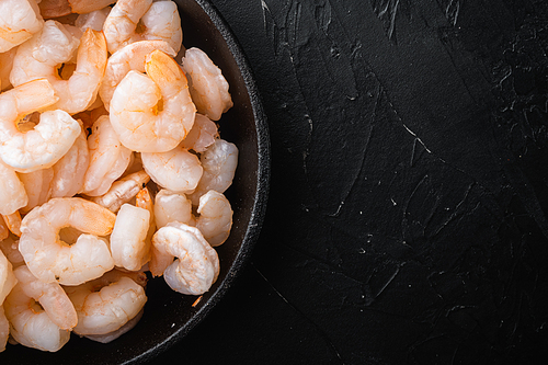 Boiled Peeled Shrimps, Prawns set, in frying cast iron pan or pot, on black stone background, top view flat lay, with copy space for text