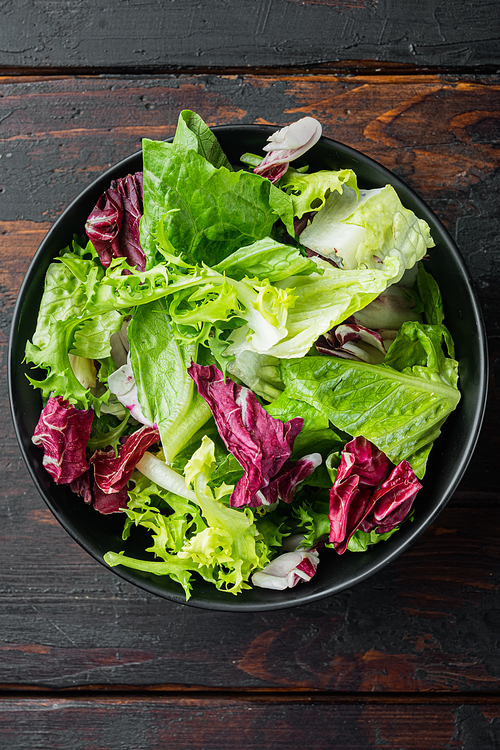 Fresh leaves of different lettuce salads, on old dark  wooden table background, top view flat lay