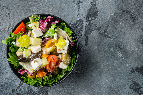 Traditional greek salad with fresh vegetables, feta and olive, on gray background, top view flat lay with copy space for text