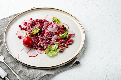 Beef Carpaccio cold appetizer set, with Radish and garnet, on plate, on white stone  background, with copy space for text