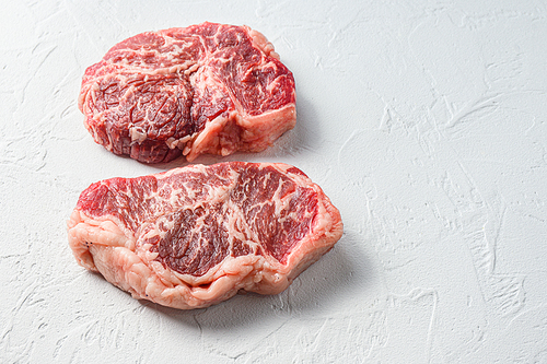 Beef  top blade steak, organic meat. White textured background. Side view with space for text