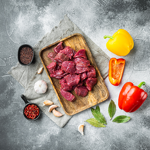 Irish raw Beef Stew Recipe ingredients set with sweet bell pepper, on gray stone background, top view flat lay, square format