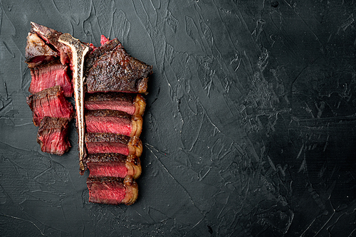 Grilled sliced t bone steak set, on black stone background, top view flat lay, with copy space for text