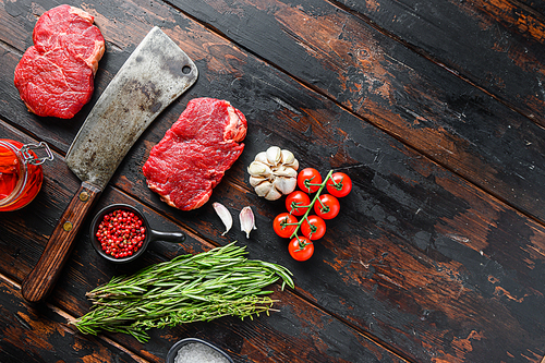 Rump steak, raw marbled beef steak, with old butcher knife cleaver, and seasonings  On dark wooden rustic table,  top view with space for text