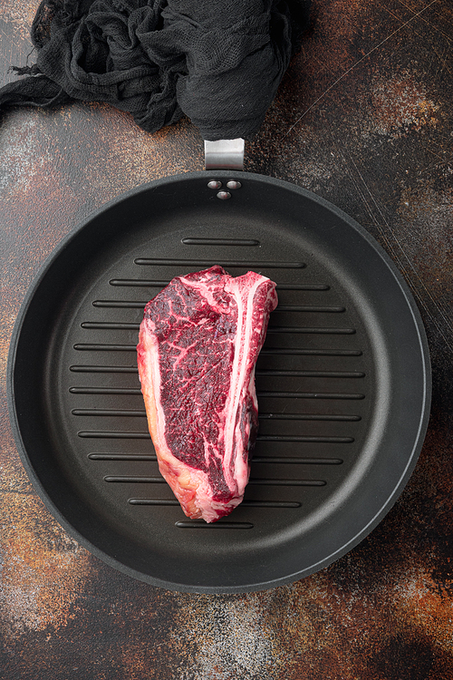 Dry-Aged Сlub raw steak prepared for cooking set, on frying cast iron pan, on old dark rustic background, top view flat lay