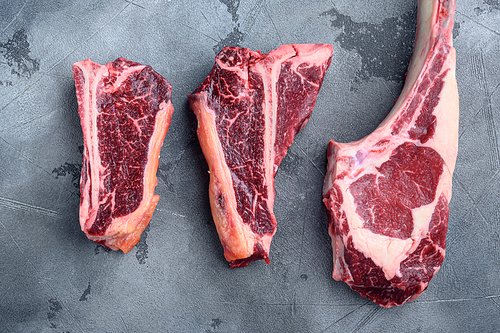 Dry aged marbled beef meat cut set, tomahawk, t bone or porterhouse and club steak, on gray stone background, top view flat lay