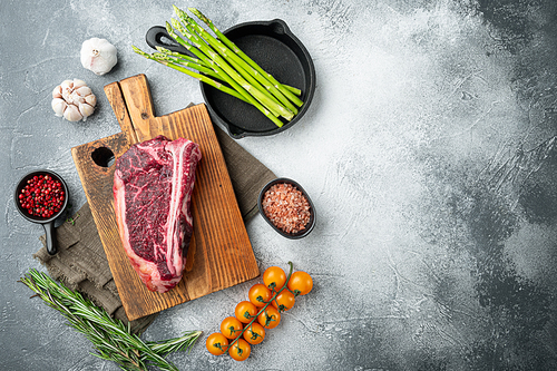 Raw fresh marbled meat black angus club steak and ingredients set, on gray stone background, top view flat lay, with copy space for text