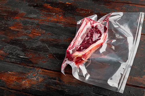 Fresh, huge and appetizing club steak in vacuum packaging set, on old dark  wooden table background, with copy space for text