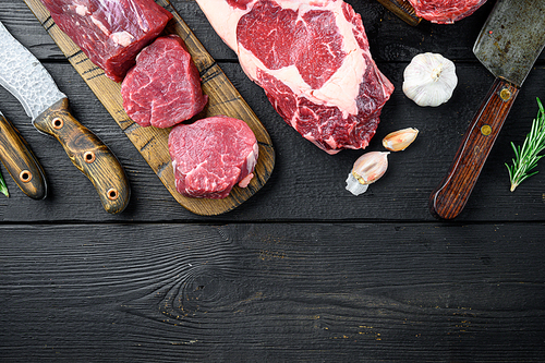 Marbled beef meat steak cut set, tomahawk, t bone, club steak, rib eye and tenderloin cuts, on black wooden background, top view flat lay, with copy space for text