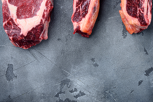 Raw prime beef meat dry aged steak set, tomahawk, t bone or porterhouse and club steak, on gray stone background, top view flat lay, with copy space for text