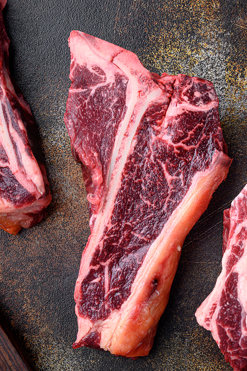 Raw fresh beef T bone steak set, on old dark rustic background, top view flat lay