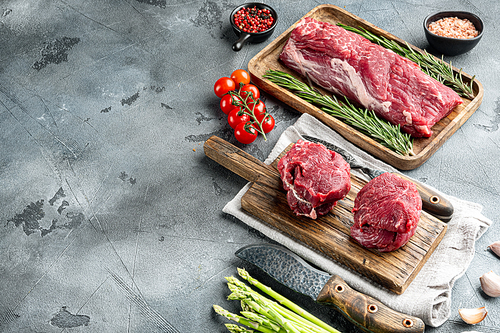 Prime Raw Fillet Mignon tenderloin steaks set, on wooden cutting board, on gray stone background, with copy space for text