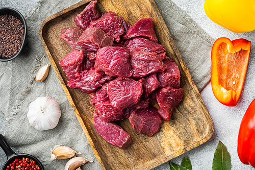 Raw meat diced for stew set with sweet bell pepper, on gray stone background, top view flat lay