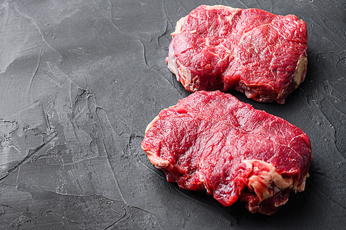 Organic rump steaks over black background, side view with space for text