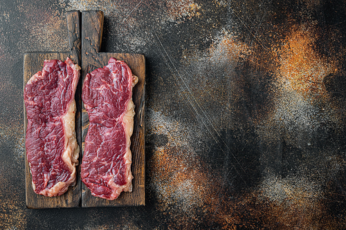 Sliced raw piece of marble beef steak, on old dark rustic background, top view flat lay with copy space for text