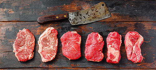 A set of different types of raw beef steaks:top blade, rump, chuck eye roll over old wooden background top view with butcher cleaver