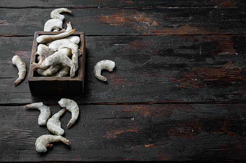 Frozen raw uncooked tiger prawns, shrimps set, on old dark  wooden table, with copy space for text