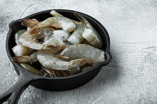 Raw tiger prawns set, in cast iron frying pan, on gray stone background