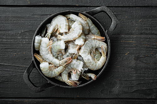 Healthy organic tiger shrimps set, in cast iron frying pan, on black wooden background, top view flat lay