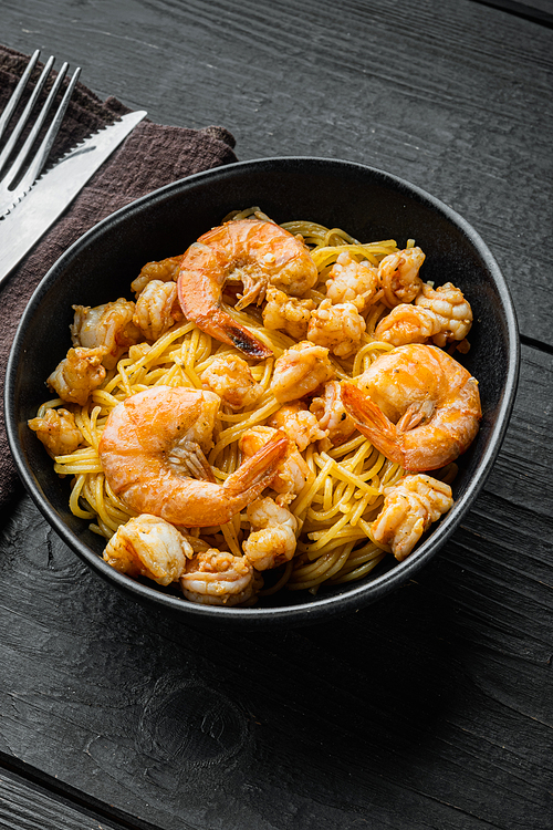 Pasta with shrimp, and pesto sauce set, in bowl, on black wooden background