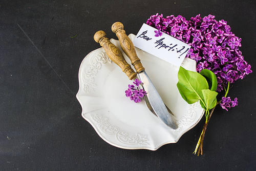 Spring table setting with bright lilac flowers on rustic background with copyspace
