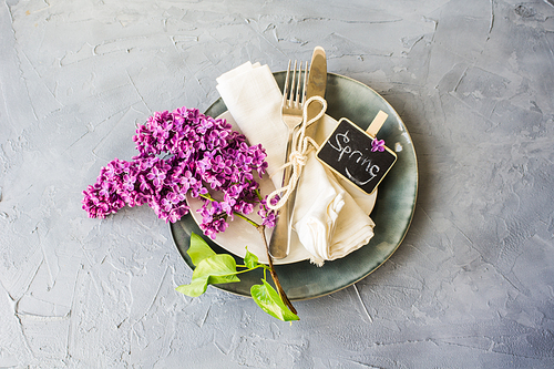 Spring table setting with bright lilac flowers on rustic background with copyspace