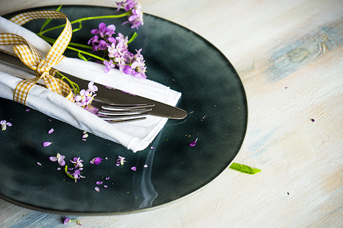 Summertime floral table setting with bright purple flowers with copysace