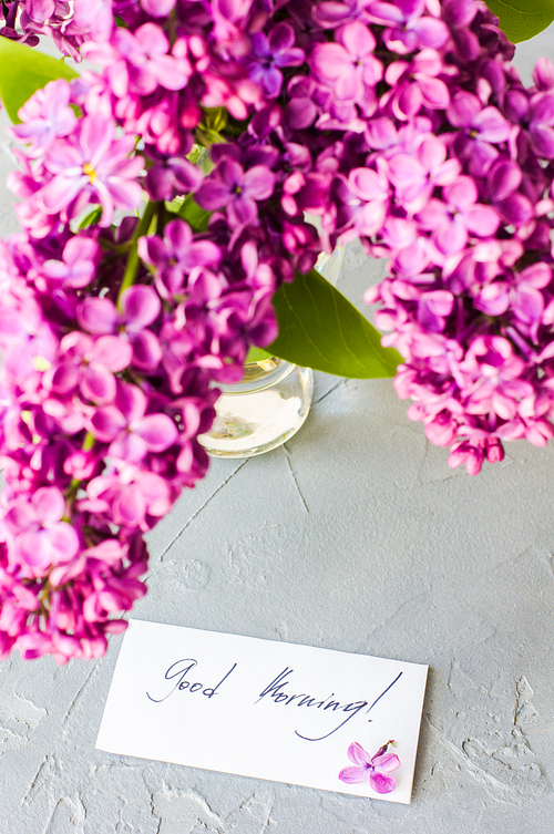 Spring interior concept with bright lilac flowers in a vintage vase on rustic wooden table