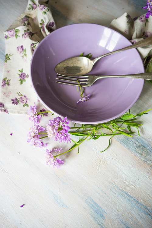 Summertime floral table setting with bright purple flowers with copysace