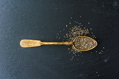 Organic chia seeds in a vintage spoon on dark wooden table with copyspace